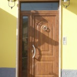 Porta di ingresso chiusa con pannello in alluminio finto legno, accessori inox