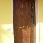 Porta di ingresso chiusa con pannello in alluminio finto legno, accessori ottone